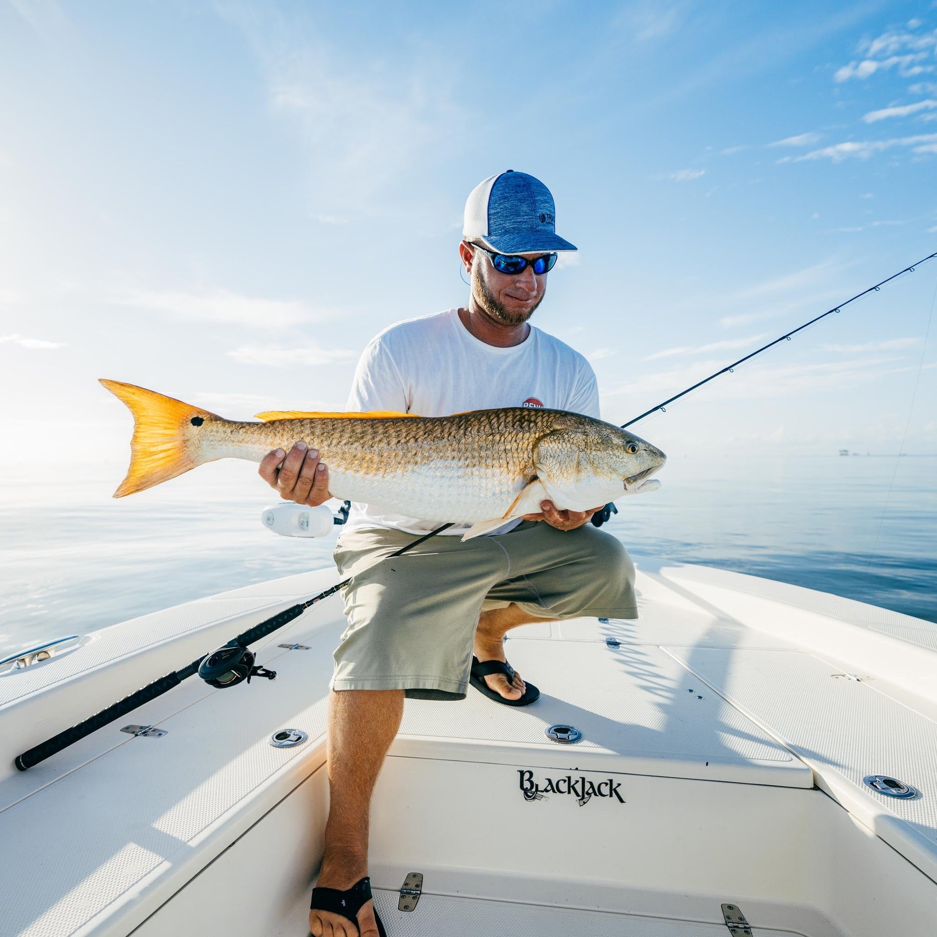 Man on boat holding large fish from the ocean